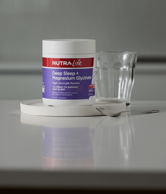 Nutra-Life Deep Sleep + Magnesium Glycinate powder container on a white surface with a glass and spoon.